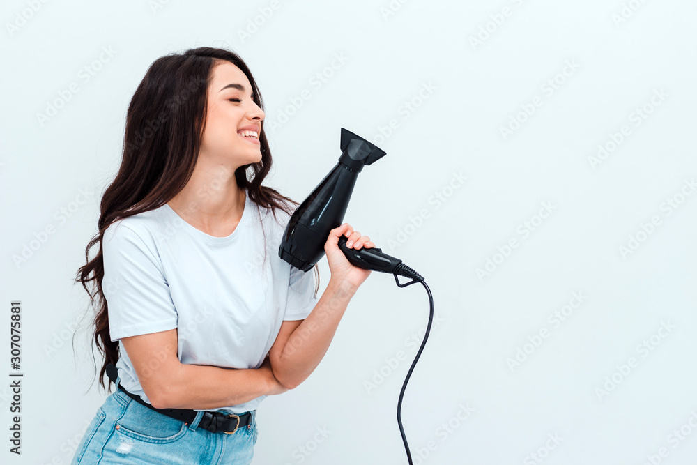Beautiful girl with long dark hair holds a hairdryer on a white background Beautiful girl with long dark hair holds a hairdryer on a white background