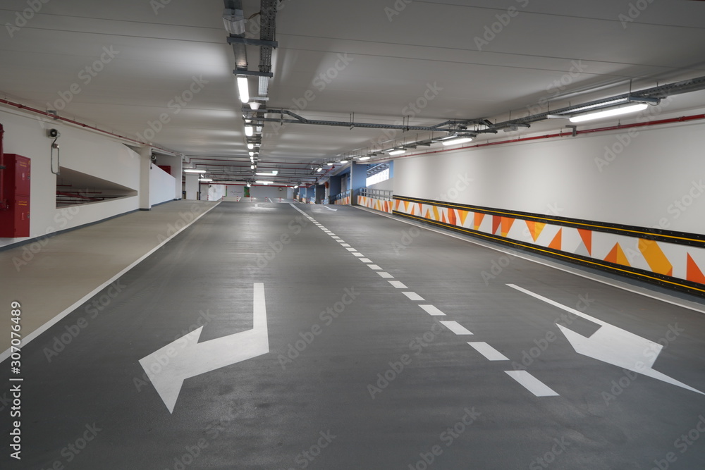 Steep paving descent to the parking lot. Brand new descending roads inside parking lot. Indoor parking lot exit passage perspective. Double lane. Steep paving descent to the parking lot. Brand new descending roads inside parking lot. Indoor parking lot exit passage perspective. Double lane.
