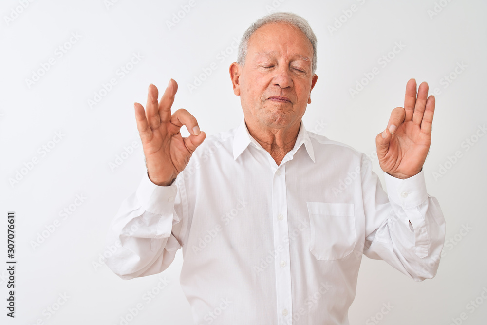 Senior grey-haired man wearing elegant shirt standing over isolated white background relax and smiling with eyes closed doing meditation gesture with fingers. Yoga concept. Senior grey-haired man wearing elegant shirt standing over isolated white background relax and smiling with eyes closed doing meditation gesture with fingers. Yoga concept.