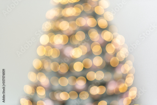 Abstract bokeh yellow lights of garlands on a Christmas tree on white background.