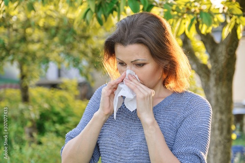 Seasonal allergies, woman with nasal wipe, sneezing, wiping nose outdoor