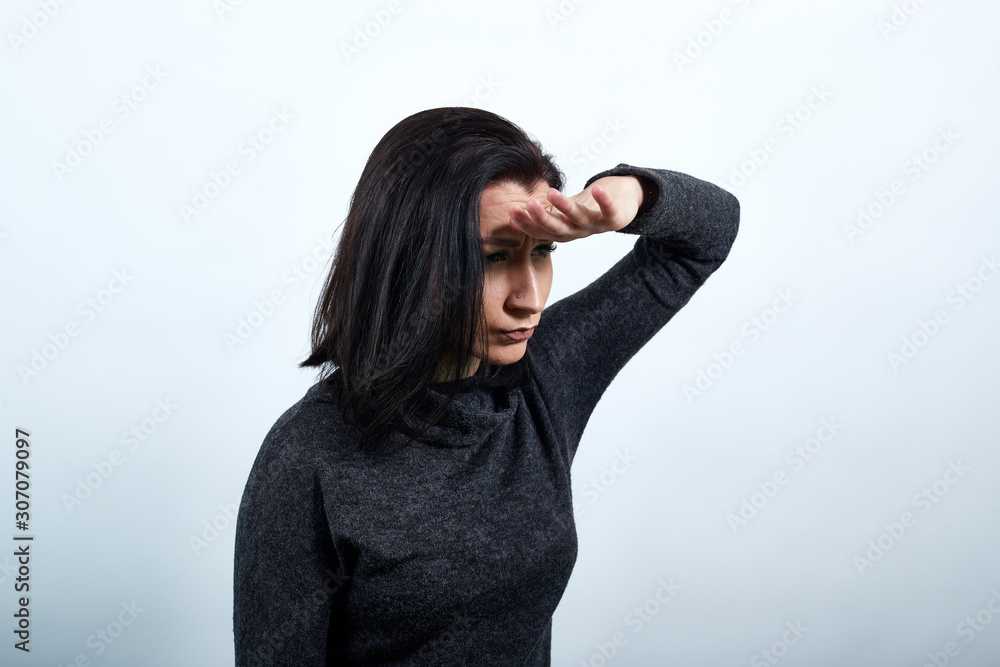 Caucasian young woman in fashion black sweater keeping hand on forehead, looking into distance over isolated white background, Lifestyle concept Caucasian young woman in fashion black sweater keeping hand on forehead, looking into distance over isolated white background, Lifestyle concept