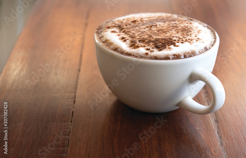 White cup of hot drinks on wood table close up.