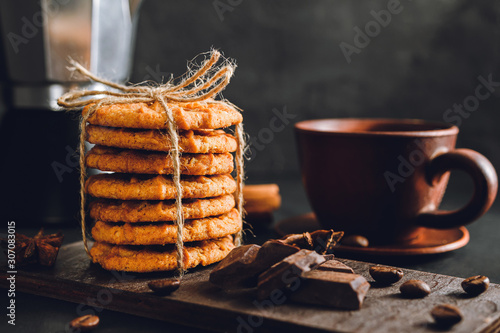 Homemade cookies and brown cup with coffee on dark background
