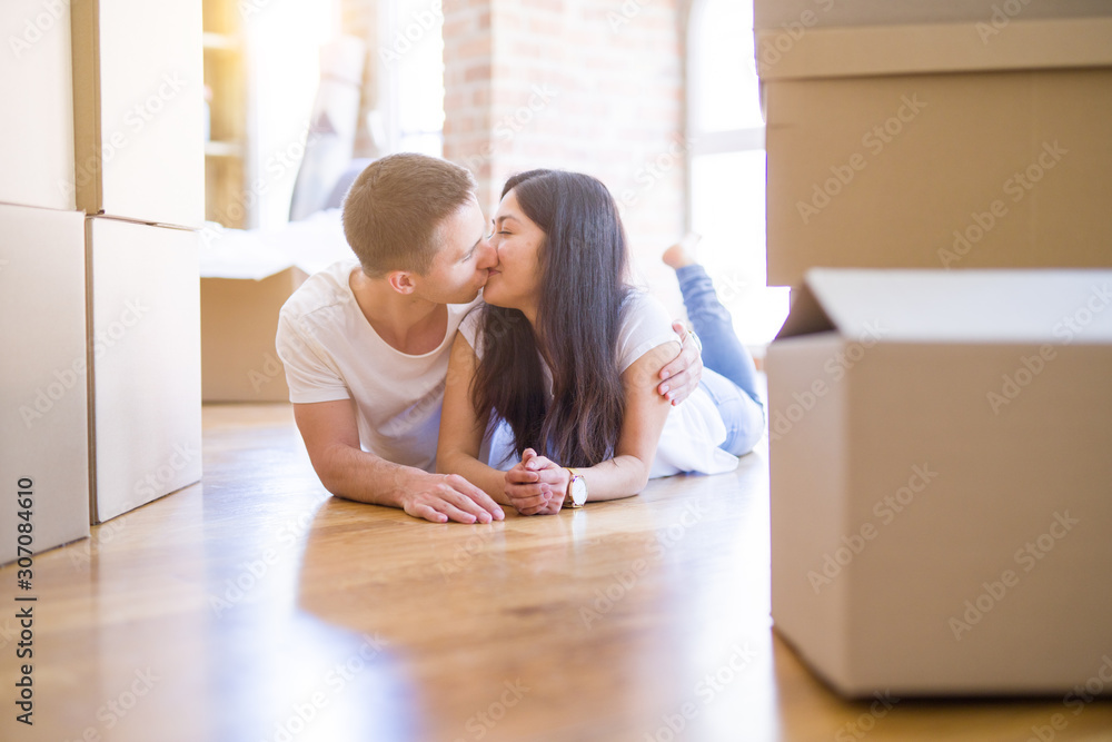 Young beautiful couple lying down at new home around cardboard boxes Young beautiful couple lying down at new home around cardboard boxes