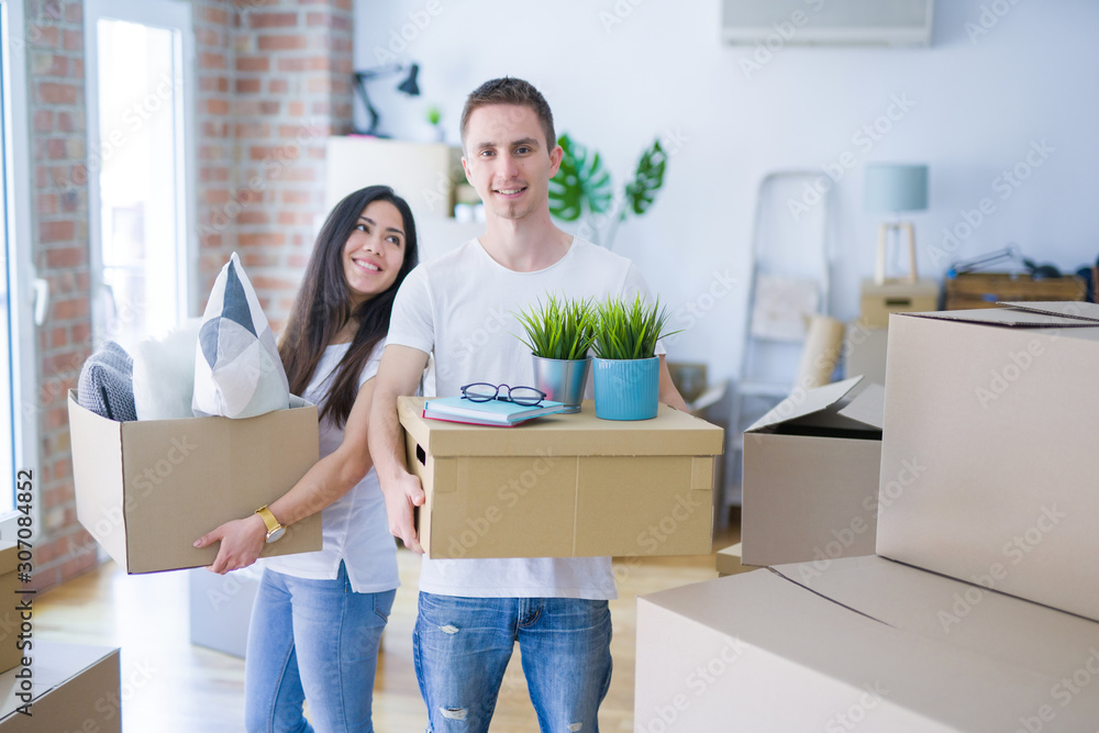 Young beautiful couple moving cardboard boxes at new home Young beautiful couple moving cardboard boxes at new home
