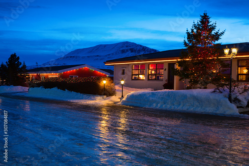 Typical Icelandic houses with Christmas decorations at the twilight near Akureyri, northern Iceland. Slippery road in the foreground.
