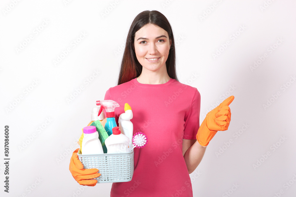 A young housewife holds in his hands cleaning products on a colored background. A young housewife holds in his hands cleaning products on a colored background.