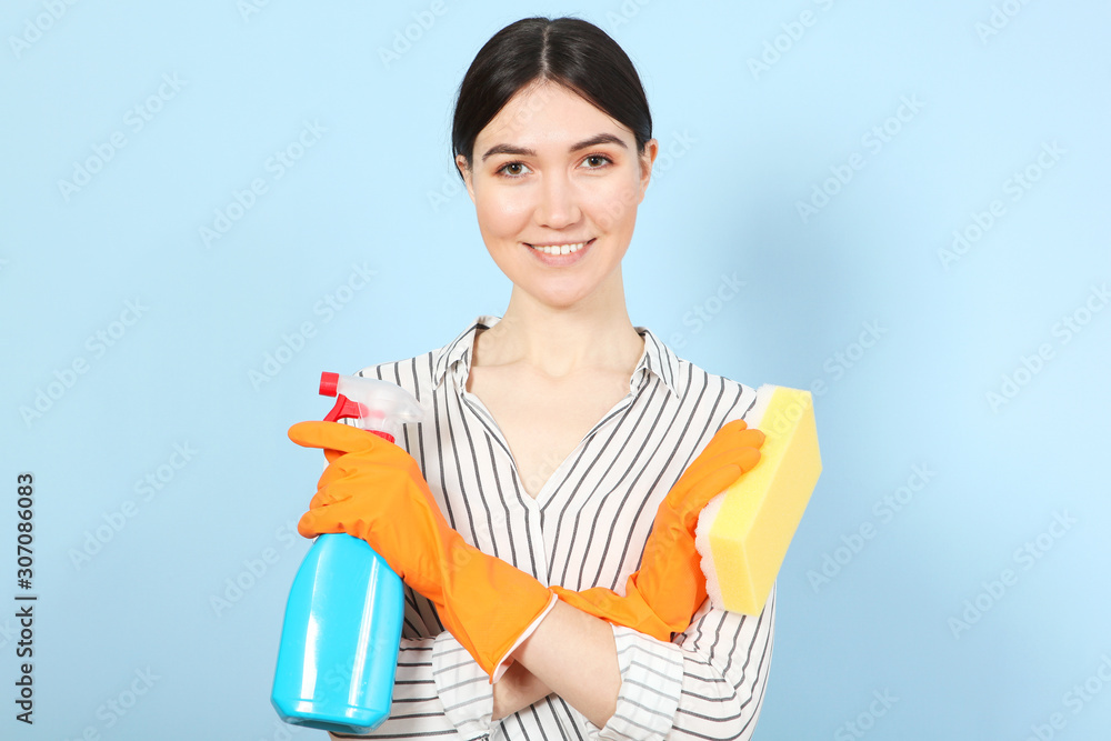 A young housewife holds in his hands cleaning products on a colored background. A young housewife holds in his hands cleaning products on a colored background.