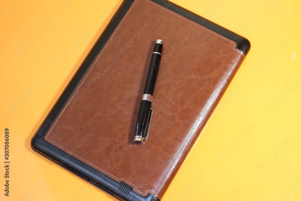 electric book and pen on a warm background electric book and pen on a warm background