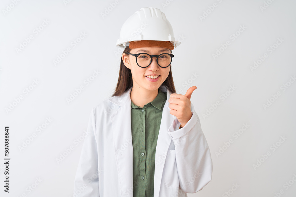 Young chinese engineer woman wearing coat helmet glasses over isolated white background doing happy thumbs up gesture with hand. Approving expression looking at the camera showing success.