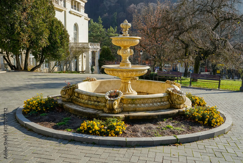 Beautiful circular water fountain with art decorations and blossomed flowers around it in front of the Casino building in Sinaia , Romania