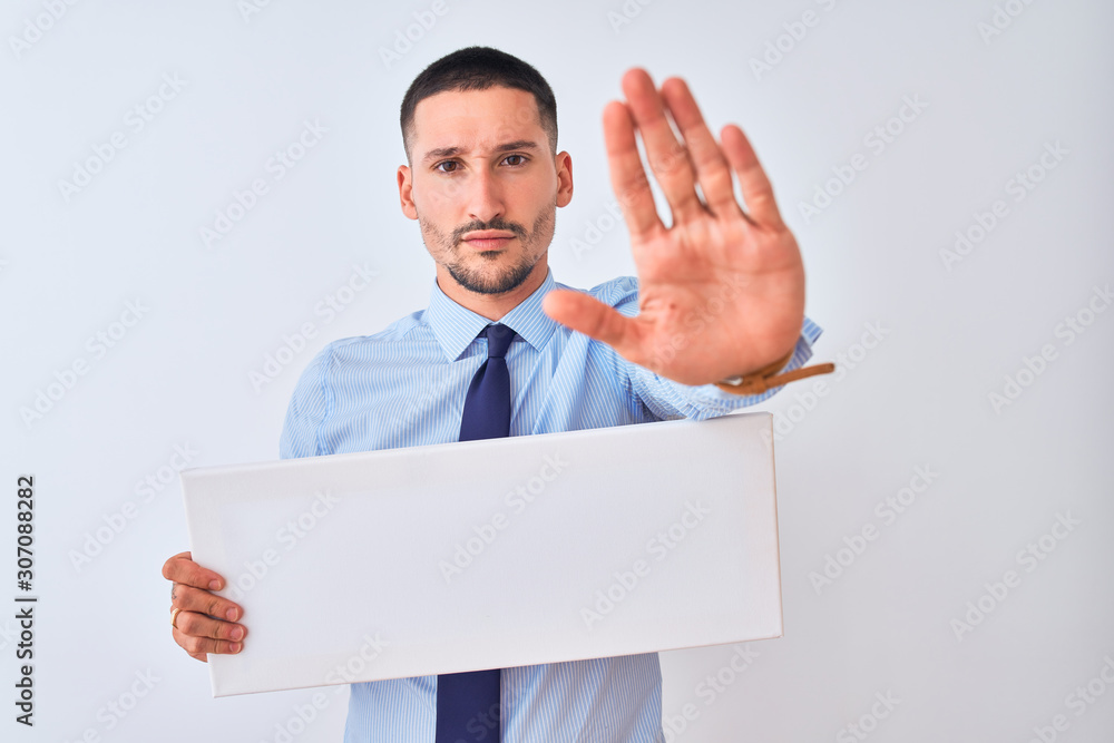 Young business man holding blank banner over isolated background with open hand doing stop sign with serious and confident expression, defense gesture Young business man holding blank banner over isolated background with open hand doing stop sign with serious and confident expression, defense gesture