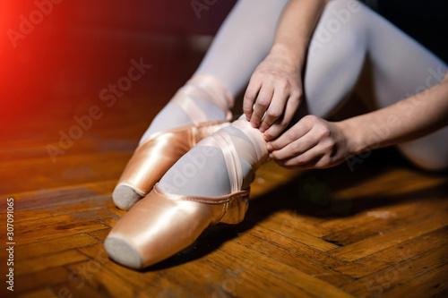 Young ballerina sitting, legs and golden shoes. Classical art concept. Preparing for dance. closeup.