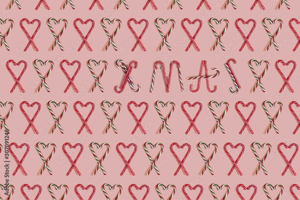 Concept Christmas pattern of candys laid of hearts and text - XMAS on a silver pink background. Concept Christmas pattern of candys laid of hearts and text - XMAS on a silver pink background.