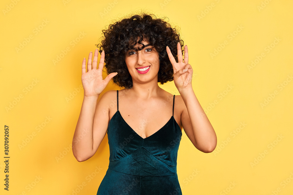 Young arab woman with curly hair wearing elegant dress over isolated yellow background showing and pointing up with fingers number eight while smiling confident and happy. Young arab woman with curly hair wearing elegant dress over isolated yellow background showing and pointing up with fingers number eight while smiling confident and happy.
