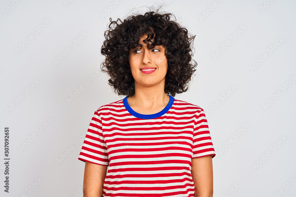 Young arab woman with curly hair wearing striped t-shirt over isolated white background smiling looking to the side and staring away thinking. Young arab woman with curly hair wearing striped t-shirt over isolated white background smiling looking to the side and staring away thinking.