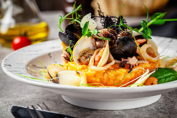 Italian food concept. Risotto with seafood, mussels, octopuses, squid. Serving dishes in a white plate. Modern serving in a restaurant. Background image. Copy space.