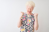 Young albino blond man wearing colorful t-shirt standing over isolated white background very happy and excited doing winner gesture with arms raised, smiling and screaming for success. Celebration 