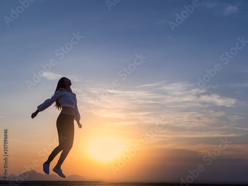 Fototapeta Naklejka Na Ścianę i Meble -  Free young woman slim body at golden sunset. Freedom and success concept,relaxing and enjoying a sunny summer holiday.
