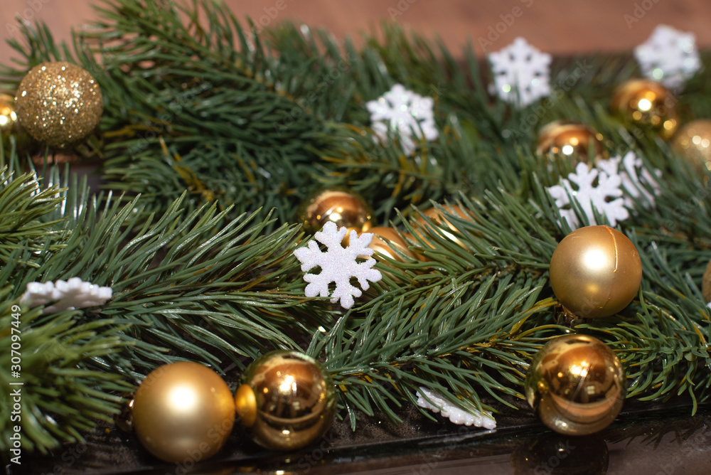 Weihnachtsdekoration mit Tannenzweigen, goldenen Mini Christbaumkugeln, weißen glitzernden Schneeflocken Nahaufnahme Close Up Detailaufnahme