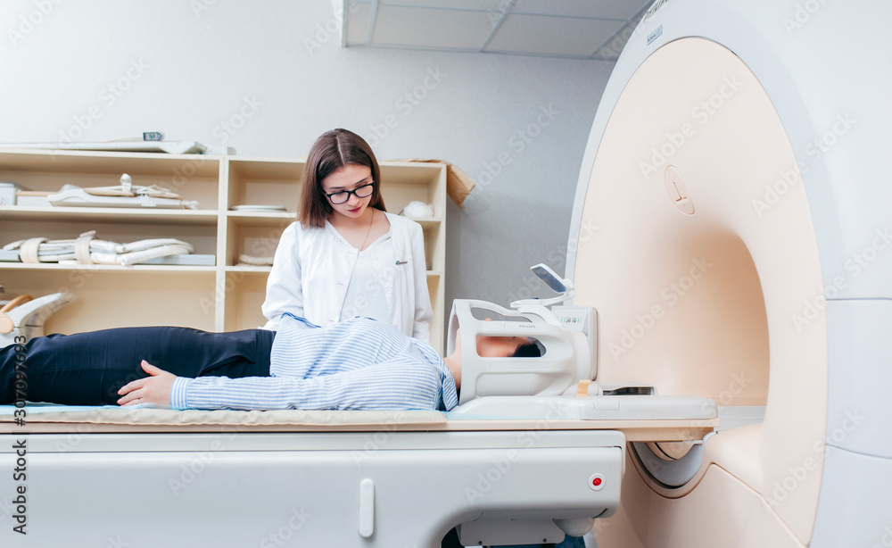 Radiologic model technician smiling help at mature female patient lying on a CT Scan bed Radiologic model technician smiling help at mature female patient lying on a CT Scan bed
