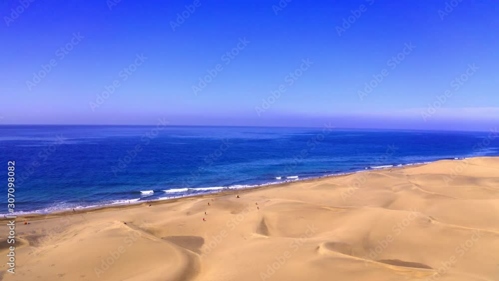 High dunes and blue beach drone flight in clear blue sky aerial flying over las dunas at las palmas beach in canaries islands. sea water in atlantic ocean High dunes and blue beach drone flight in clear blue sky aerial flying over las dunas at las palmas beach in canaries islands. sea water in atlantic ocean