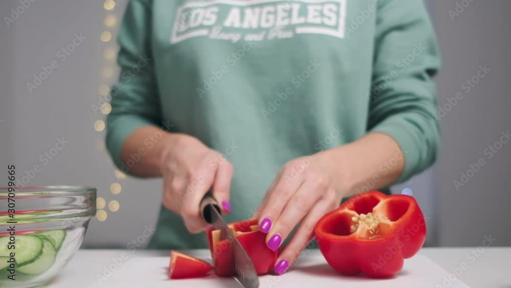 Close up. The woman with a knife cuts ripe, red pepper for salad. Healthy diet. Slow motion. Close up. The woman with a knife cuts ripe, red pepper for salad. Healthy diet. Slow motion.