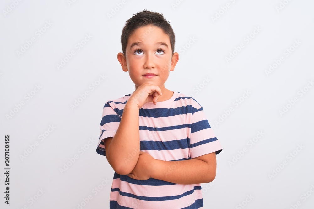 Beautiful kid boy wearing casual striped t-shirt standing over isolated white background with hand on chin thinking about question, pensive expression. Smiling with thoughtful face. Doubt concept. Beautiful kid boy wearing casual striped t-shirt standing over isolated white background with hand on chin thinking about question, pensive expression. Smiling with thoughtful face. Doubt concept.