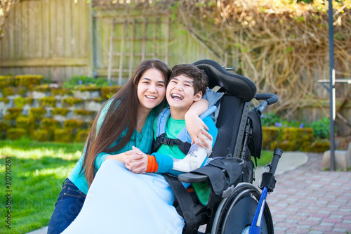 Disabled boy in wheelchair smiling with teen sister on patio