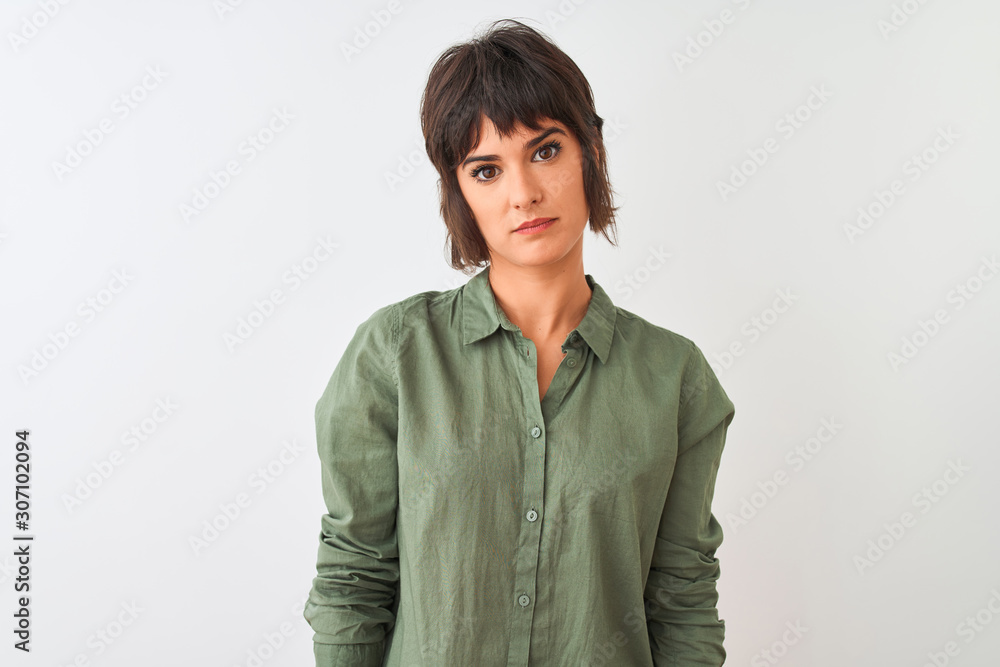 Young beautiful woman wearing green casual shirt standing over isolated white background with serious expression on face. Simple and natural looking at the camera. Young beautiful woman wearing green casual shirt standing over isolated white background with serious expression on face. Simple and natural looking at the camera.