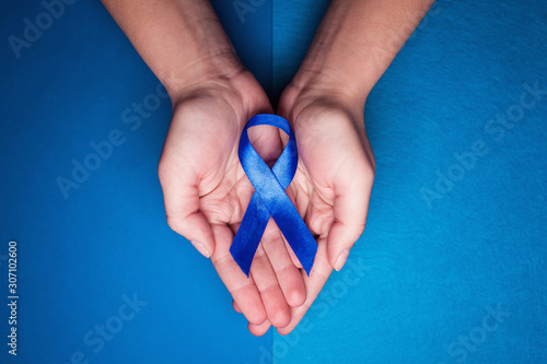 blue ribbon in support of trafficking and sexual slavery. Blue ribbon on female hands on a blue background