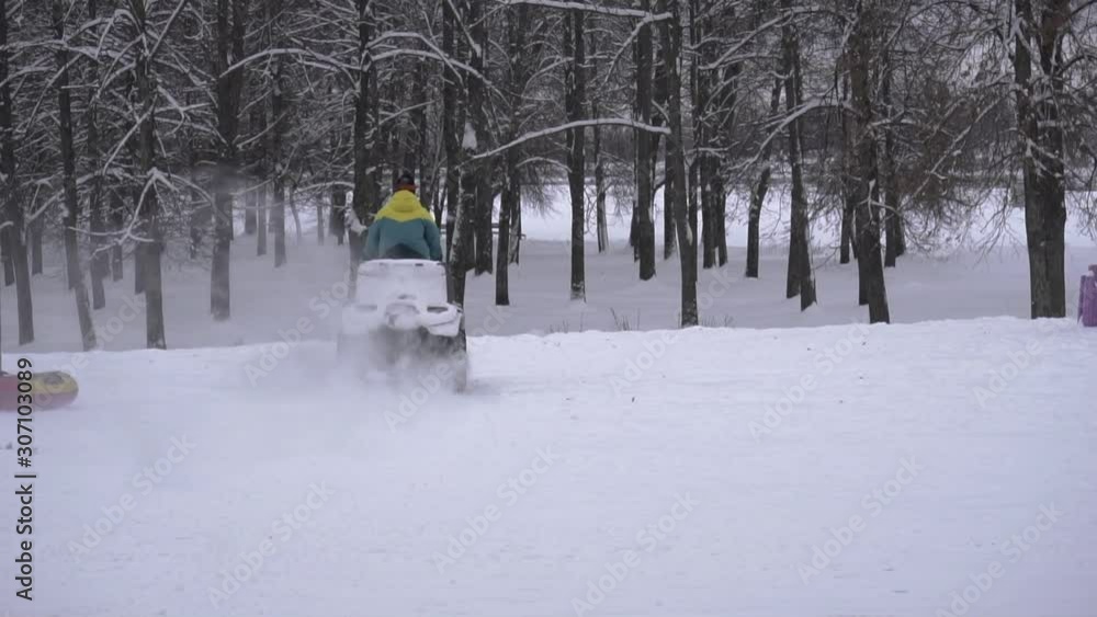 One riding an all-terrain vehicle in winter on a snowy beach along the river bank. Guy in ski mask and glasses moves on a Quad bike during ATV racing on a motocross track in slow motion in daytime One riding an all-terrain vehicle in winter on a snowy beach along the river bank. Guy in ski mask and glasses moves on a Quad bike during ATV racing on a motocross track in slow motion in daytime