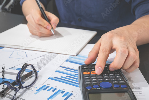 business man using calculator to calculate financial document on table in office