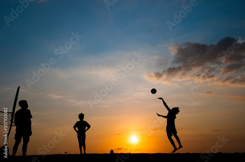 Domestic Life of silhouette young adults playing beach volley ball at beach on sunset