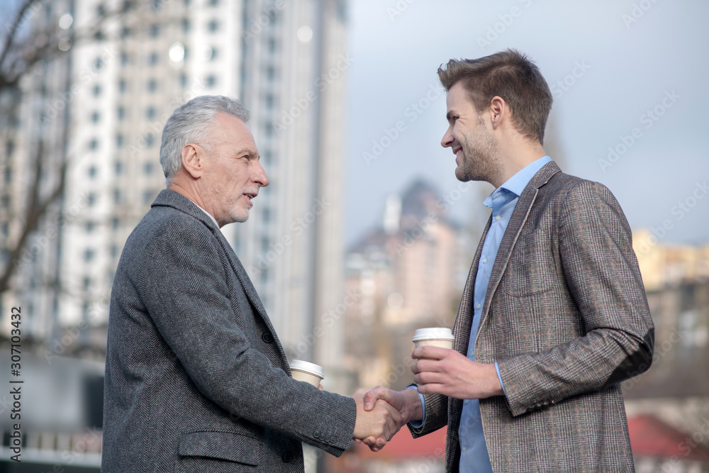Young businessman and his mature mentor shaking hands Young businessman and his mature mentor shaking hands