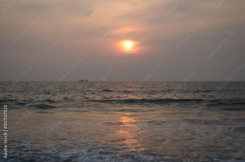 Reflection of sun on light green water of Arabian sea on a dusky sunset at Goa India