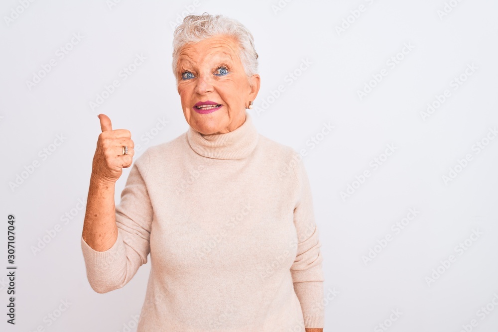 Senior grey-haired woman wearing turtleneck sweater standing over isolated white background doing happy thumbs up gesture with hand. Approving expression looking at the camera showing success. Senior grey-haired woman wearing turtleneck sweater standing over isolated white background doing happy thumbs up gesture with hand. Approving expression looking at the camera showing success.