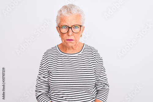 Senior grey-haired woman wearing striped navy t-shirt glasses over isolated white background skeptic and nervous, frowning upset because of problem. Negative person.