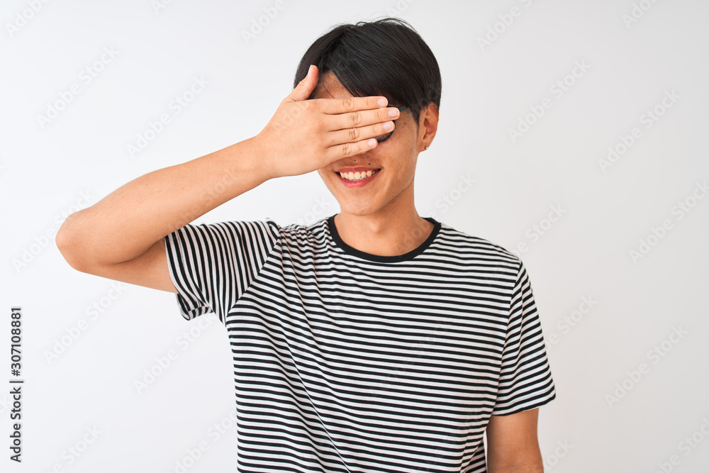Chinese man wearing glasses and navy striped t-shirt standing over isolated white background smiling and laughing with hand on face covering eyes for surprise. Blind concept. Chinese man wearing glasses and navy striped t-shirt standing over isolated white background smiling and laughing with hand on face covering eyes for surprise. Blind concept.