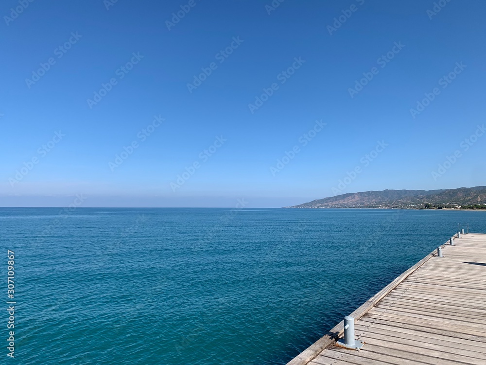 Wooden jetty over the beautiful mediterranean sea with blue sky
