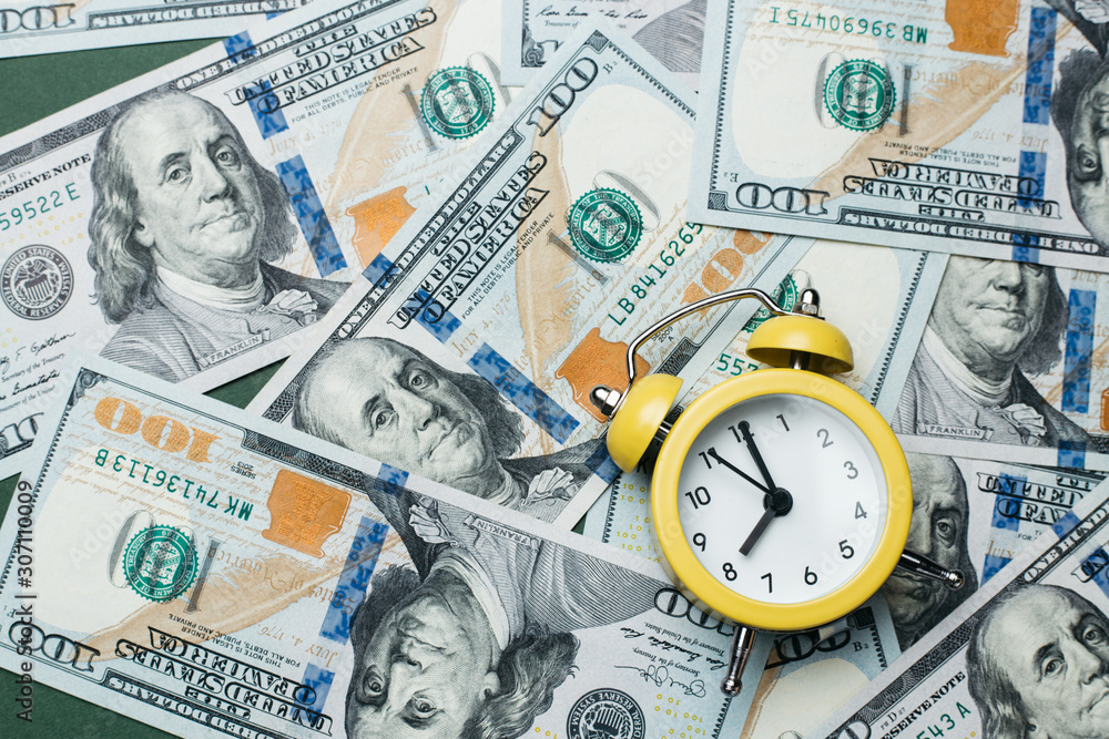 Yellow alarm clock on the stack of one hundred american dollars bills. Credit, deposit and mortgage concept. Yellow alarm clock on the stack of one hundred american dollars bills. Credit, deposit and mortgage concept.
