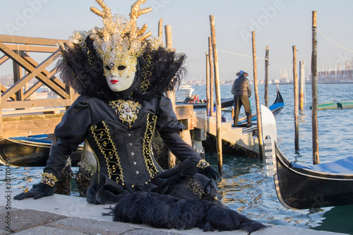 Female mask at the Venice carnival wearing a black and gold dress