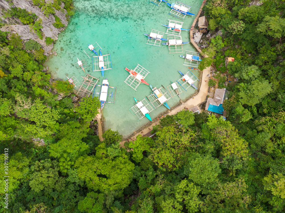 Blue crystal water in paradise Bay with boats on the wooden pier at Kayangan Lake in Coron island, Palawan, Philippines.