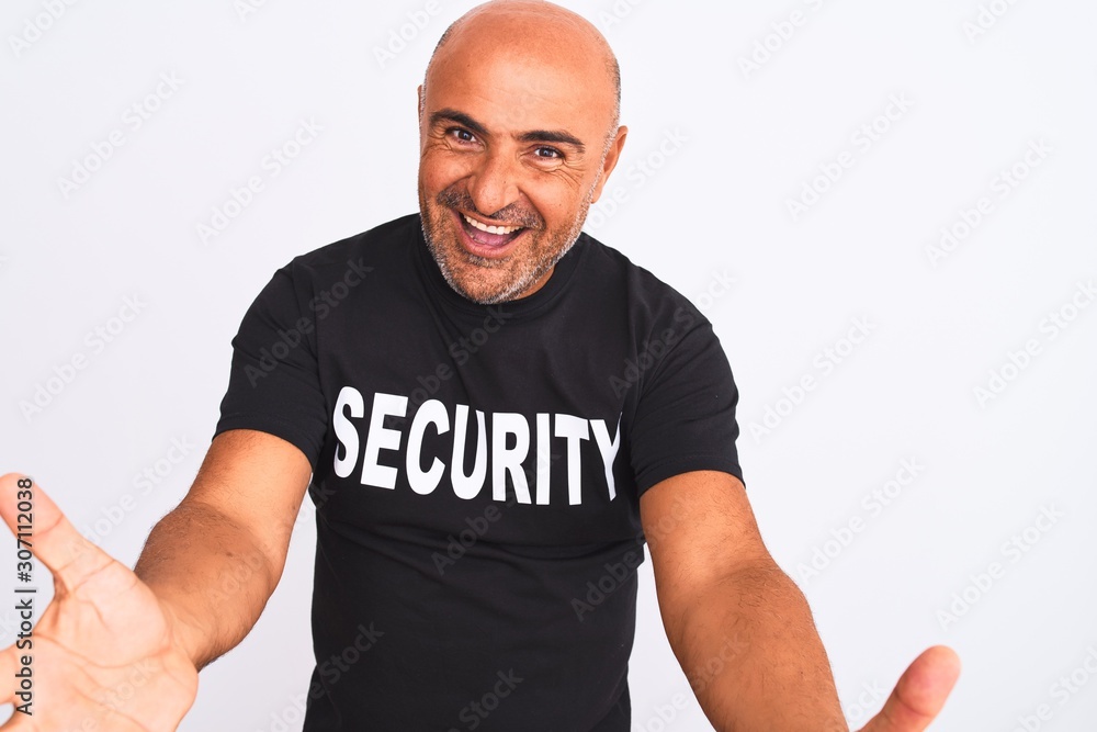 Middle age safeguard man wearing security uniform standing over isolated white background looking at the camera smiling with open arms for hug. Cheerful expression embracing happiness. Middle age safeguard man wearing security uniform standing over isolated white background looking at the camera smiling with open arms for hug. Cheerful expression embracing happiness.