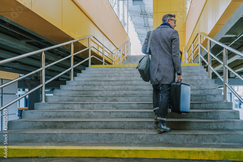 Stylish gentleman with travel suitcase walking up the stairs © Yakobchuk Olena