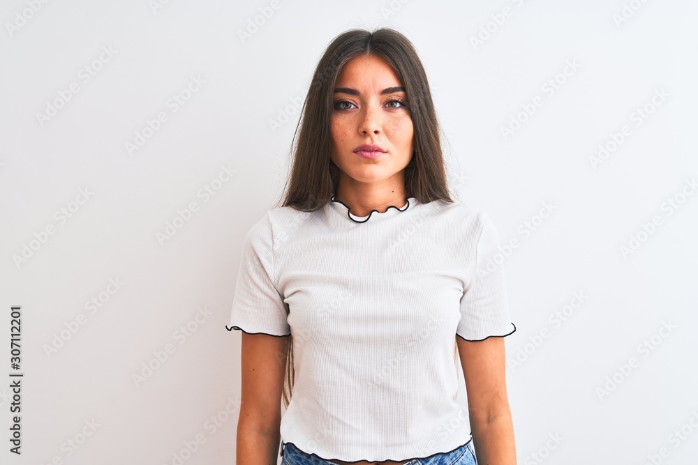 Young beautiful woman wearing casual t-shirt standing over isolated white background with serious expression on face. Simple and natural looking at the camera. Young beautiful woman wearing casual t-shirt standing over isolated white background with serious expression on face. Simple and natural looking at the camera.