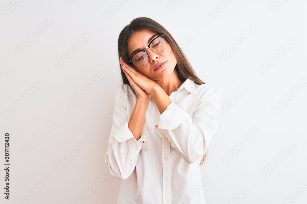 Young beautiful businesswoman wearing glasses standing over isolated white background sleeping tired dreaming and posing with hands together while smiling with closed eyes. Young beautiful businesswoman wearing glasses standing over isolated white background sleeping tired dreaming and posing with hands together while smiling with closed eyes.