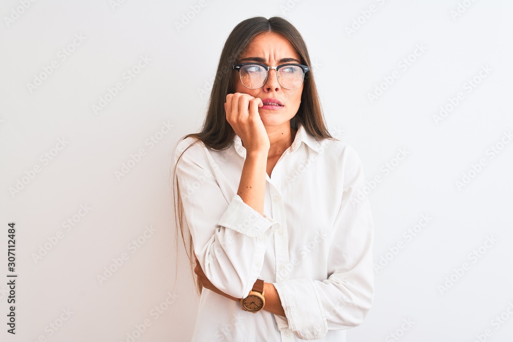 Young beautiful businesswoman wearing glasses standing over isolated white background looking stressed and nervous with hands on mouth biting nails. Anxiety problem. Young beautiful businesswoman wearing glasses standing over isolated white background looking stressed and nervous with hands on mouth biting nails. Anxiety problem.