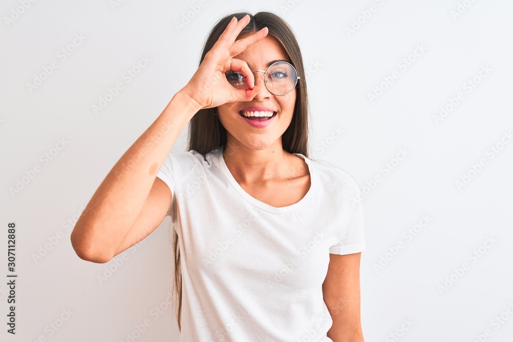 Young beautiful woman wearing casual t-shirt and glasses over isolated white background doing ok gesture with hand smiling, eye looking through fingers with happy face. Young beautiful woman wearing casual t-shirt and glasses over isolated white background doing ok gesture with hand smiling, eye looking through fingers with happy face.